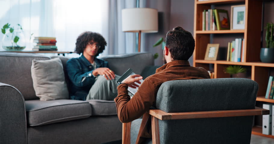 Advice, talking and psychology with man on sofa for counseling, mental health and discussion. Therapy session, trauma rehabilitation and healing with person in clinic for support and progress