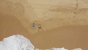 4K drone flying above couple lying in star-shaped poses on sandy beach washed with foamy turquoise waves. Summer holiday, ocean holiday, relaxation concept. Tangalle, Sri Lanka. - Powered by Shutterstock - Get 15% off with code: PIKWIZARD15