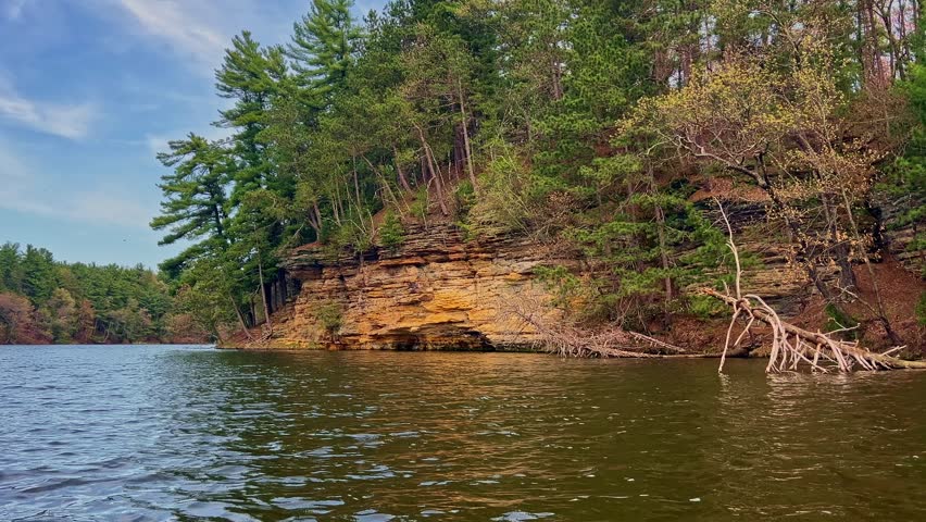 A stunning sunset view from the water at Mirror Lake, Reedsburg, with vibrant skies reflecting off the tranquil lake and dramatic cliffs creating a picturesque scene