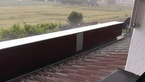 heavy rain storm with falling ice pellets on a roof and farmland in spring - Powered by Shutterstock - Get 15% off with code: PIKWIZARD15