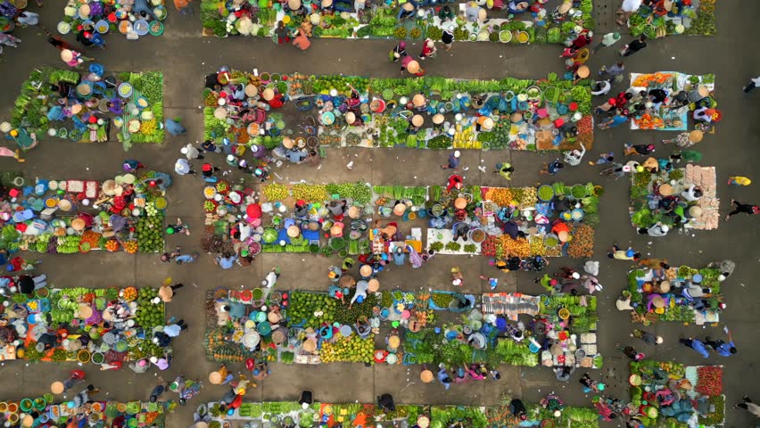 Aerial top-down view of vibrant Vietnamese market with fruits, vegetables, and people in conical hats. Colorful local culture and traditional street commerce in Southeast Asia.