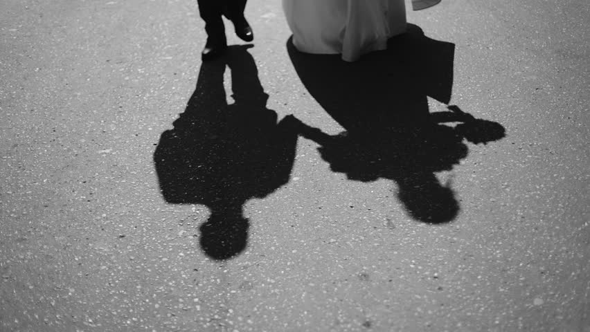The shadows of a couple in love are visible on the sidewalk. A man and a woman are walking together