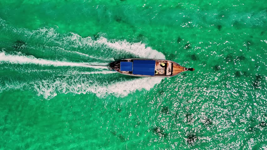 Traditional longtail boat sailing through vibrant turquoise waters in the Phi phi islands, a tropical paradise in Thailand