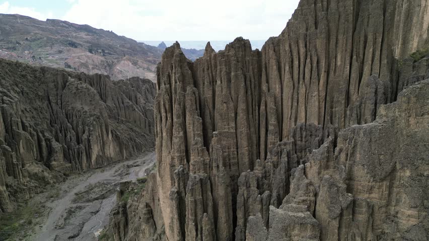 An aerial landscape view of rugged canyon with unique rock formations under cloudy sky in the Valley of the Souls in La Paz, Bolivia