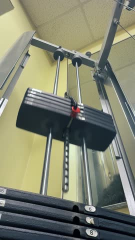 Low-angle view of a weight stack on a gym machine, emphasizing metal rods, weight plates, and pin selector. A powerful visual for fitness, strength training, and gym motivation content. 14669	