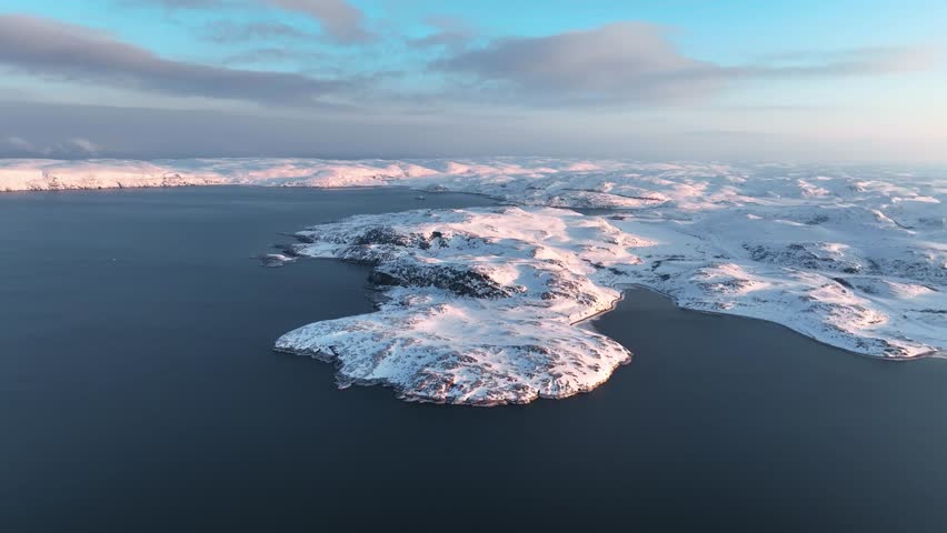 Aerial view of snow-covered islands emerging from the calm waters of the Barents Sea in the Arctic, Russia