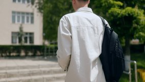 Teenage schoolboy with a backpack and books walking toward the school entrance. Early morning view of a student arriving at school for another day. - Powered by Shutterstock - Get 15% off with code: PIKWIZARD15