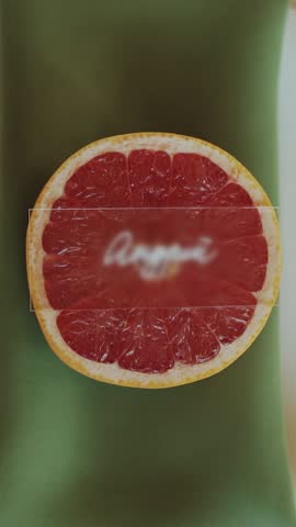 A green napkin with a grapefruit slice sits on a plate on the table, as a wedding serve, white classic plate and golden color fork and knife laying near, slow motion. Vertical video