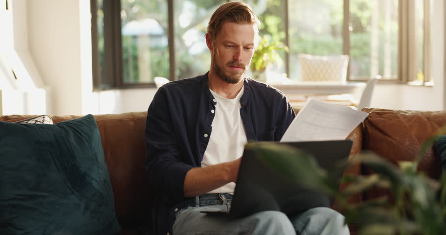 Happy, documents and man in home on laptop for budget, financial review and mortgage payment. Living room, reading and person with paperwork for insurance, investment and finance bills on computer