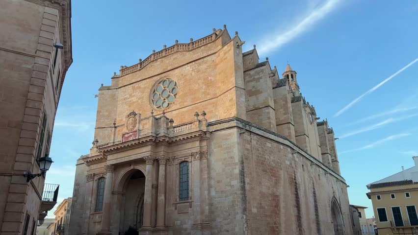The Cathedral Basilica of Ciutadella de Menorca, an iconic historical site in Spain, showcasing stunning architecture and intricate stonework beneath a clear blue sky.