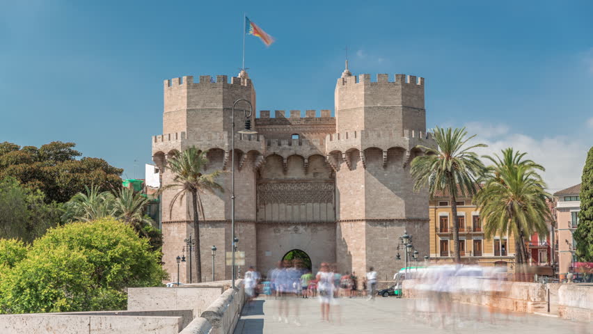 Serrans Towers (Torres de Serranos) timelapse hyperlapse in Valencia, Spain. A grand medieval gate from the city's ancient walls. Bustling street scene under a blue sky frames this historic landmark