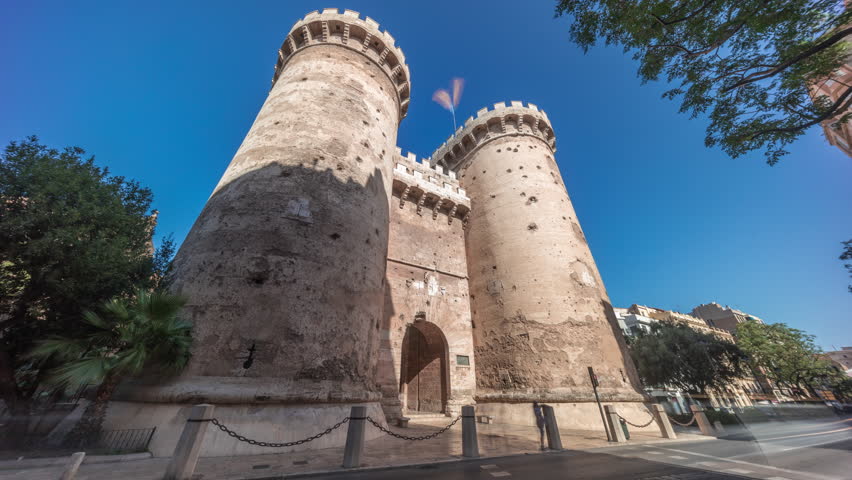 Towers of Quart timelapse hyperlapse in Valencia, Spain. Historical medieval gate, part of the ancient city walls. Popular landmark with a rich cultural heritage. Blue sky and street traffic scene.