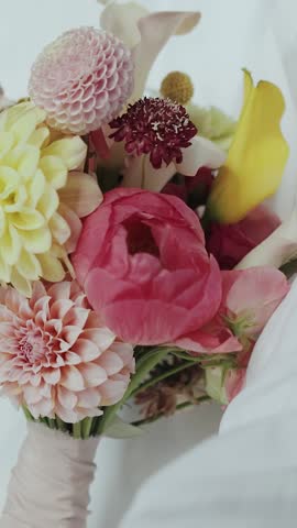 A close-up shot of a wedding and beautifully arranged floral bouquet that features vibrant, cheerful colors. Vertical video