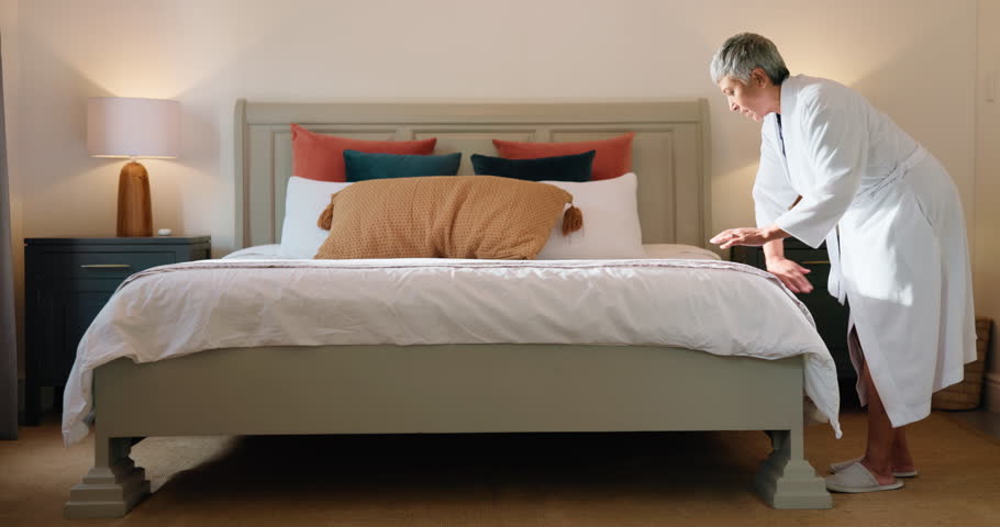 Bedroom, woman and making bed in home, chores or routine for maintenance of mattress, tidy or clean. Neat, morning and organizing pillows, housework and mature person with blanket in apartment