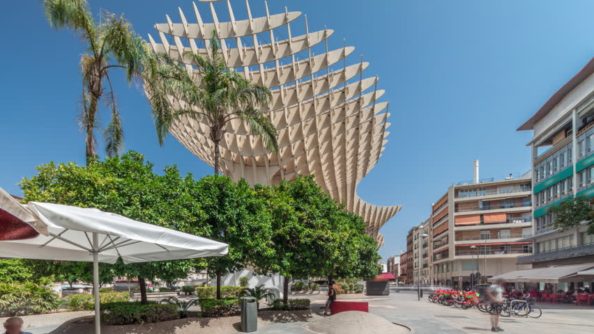 Metropol Parasol in Encarnacion Square timelapse hyperlapse, a futuristic wooden structure with a panoramic walkway and an archaeological museum. Blue sky, trees and cityscape in Seville, Spain.