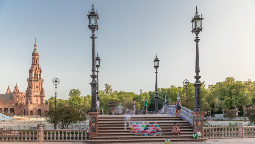 Plaza de Espana in Seville timelapse hyperlapse, a grand architectural complex in Maria Luisa Park built for the Ibero-American Exposition. Bridge with tourists, canal and vintage streetlights