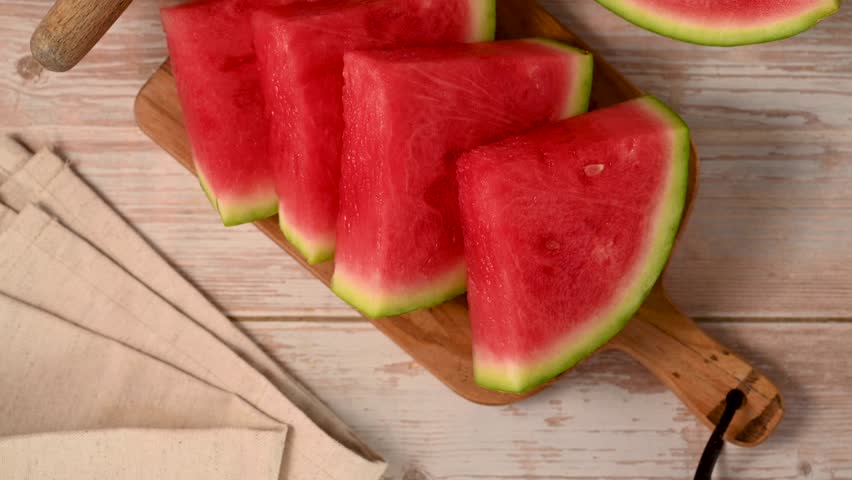 Slices of fresh watermelon on bright rustic wooden table.