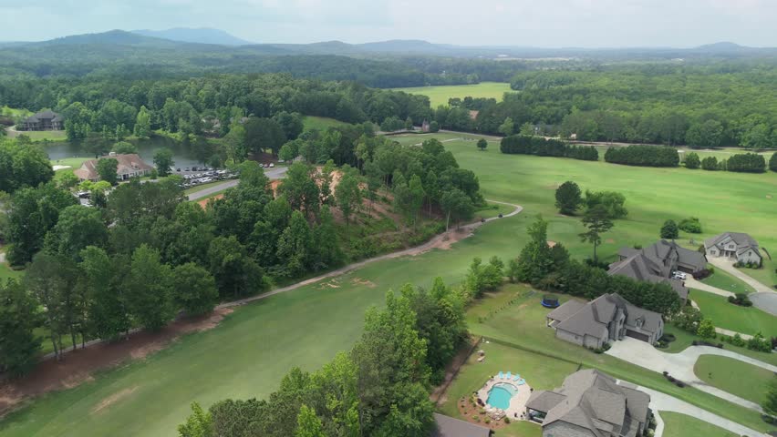 Drone footage of Cider Ridge in Oxford, Alabama, showcasing the championship golf course, surrounding residential neighborhood, scenic fairways, and tree-lined streets on a sunny day.