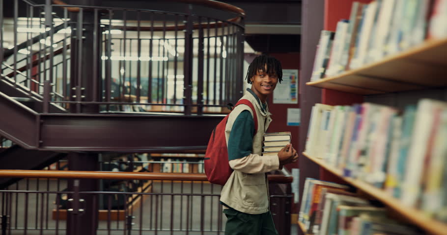 Black man, student and walk with books in library for search, knowledge and information for scholarship. Male person, carry and textbooks for learning, education and study resources of admission test