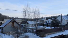 After a snowfall snow lies on the ground and tree branches. Нouses with snow-covered roofs stand in front of the pine forest. Smoke is coming out of the chimney. The winter sun rises at dawn. Blue sky - Powered by Shutterstock - Get 15% off with code: PIKWIZARD15