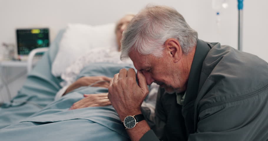 Crying, sad and elderly couple in hospital bed with bad news, terminal diagnosis or medical results. Healthcare, marriage and man with woman praying for healing, support and hope for surgery recovery