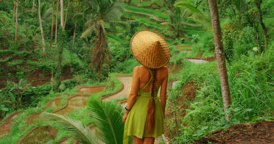 Woman in straw hat overlooking terraced rice fields in Bali during summer trip