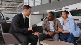 Car salesman showing contract to african american couple in dealership - Powered by Shutterstock - Get 15% off with code: PIKWIZARD15