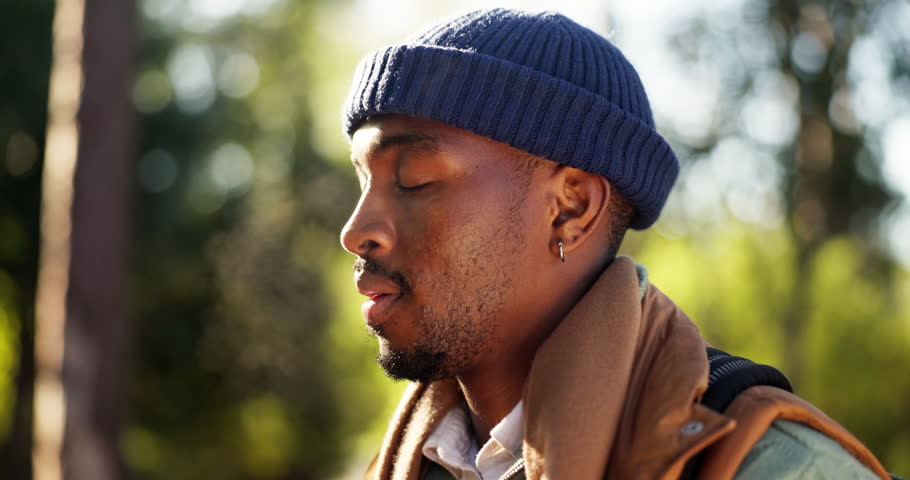 Breathing, fresh air and man in woods, peace and wellness for traveller in nature, happy or holiday. Outdoor, hiker and black person with smile on break, calm and mindfulness on vacation in forest