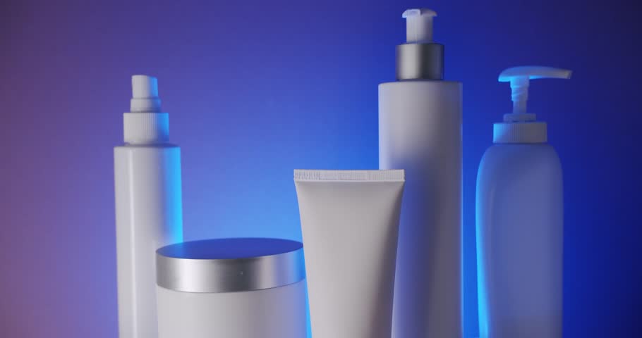 White Bottle and tubes for cosmetics on a blue background in studio, camera zoom out. Natural cosmetics production for hair and skin care. Glossy cosmetic jar with cream.