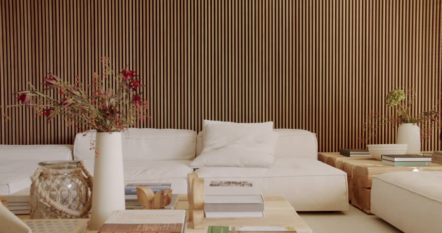 Modern living room interior with wooden slat wall, white sofa, coffee table, and stylish decor. Warm sunlight illuminates through the blinds, creating a cozy ambiance, ideal for home decor videos.