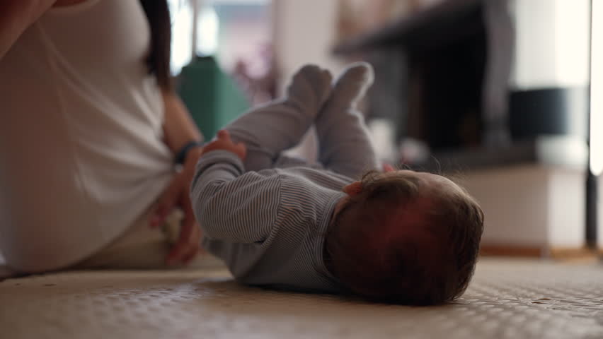 Baby rolling over on mat indoors, developing motor skills, early physical growth, learning body coordination, milestone in infant movement, peaceful home setting