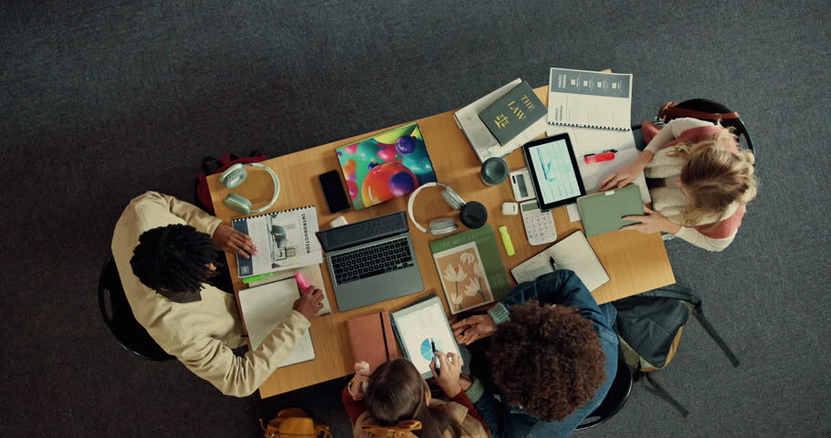 Studying, group and exchanging notes in library, above and students with tech for knowledge and app. Education, people and learning for exam in university, planning and preparing test with books