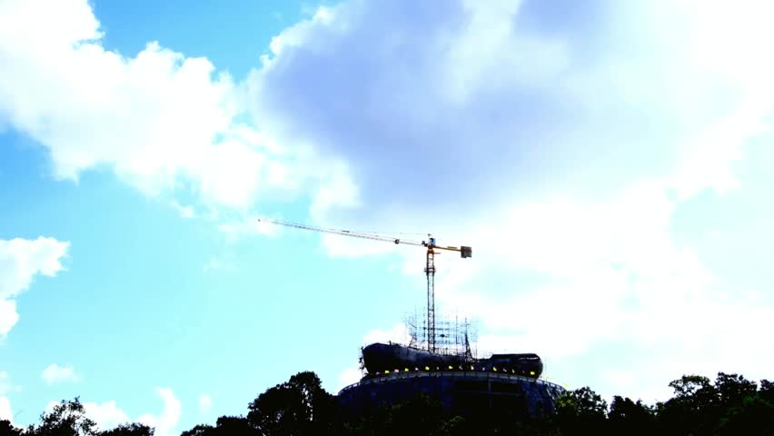Construction Crane Silhouette Against Blue Sky with Clouds