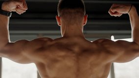 A powerful image of a young man flexing his back muscles, showcasing strength and dedication in a gym setting. Young Male Athlete Flexing Muscles in Modern Gym Environment - Powered by Shutterstock - Get 15% off with code: PIKWIZARD15