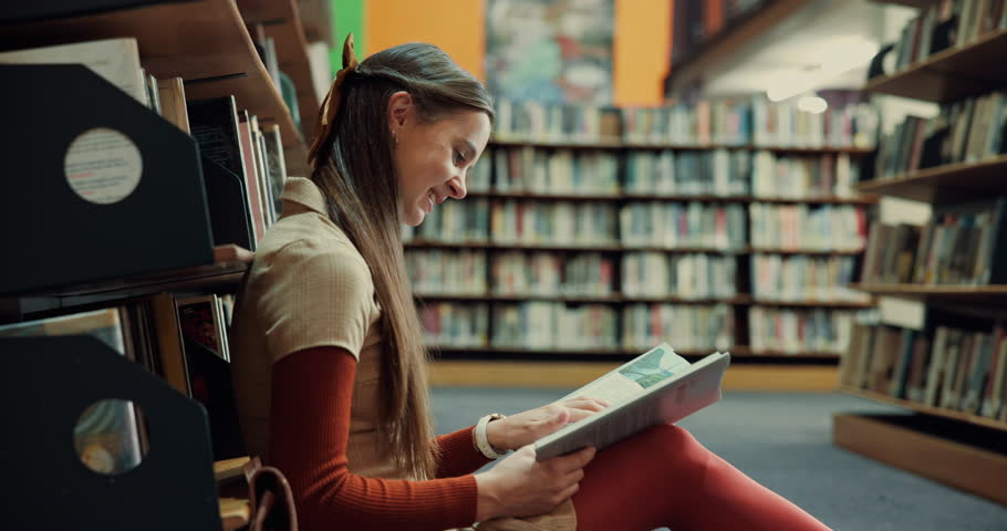 Happy woman, laughing or reading with book in library for comedy story, funny joke or humor. Female person, student or studying with smile or novel on floor for comic, genre or amusement by bookshelf