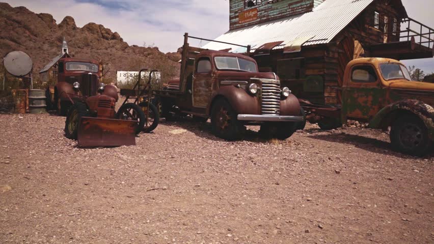 Slow walk to the right of some old trucks in the ghost town of Nelson Nevada