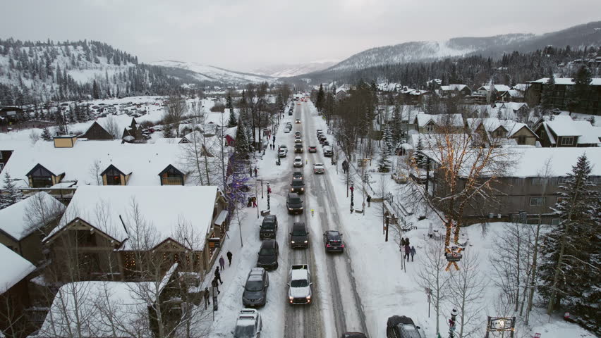 An aerial of a peaceful and beautiful snow-covered Breckenridge, as cars carrying skis and snowboards drive into the popular Colorado mountain town for a ski vacation at the world famous resort.
