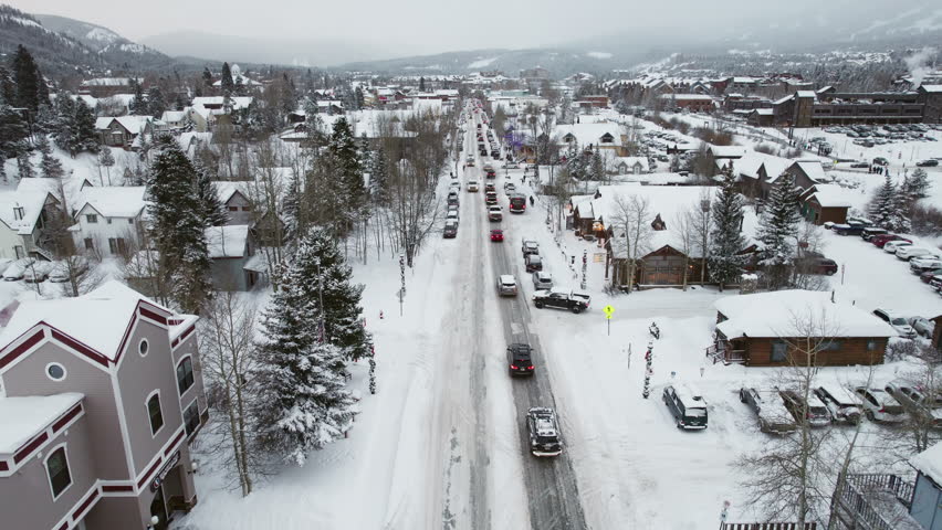 Smooth overhead of cars carrying skis and snowboards in winter and snow, driving down the main road in Breckenridge, the popular Colorado mountain town for a ski vacation at the world famous resort.