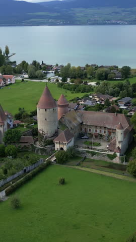 Vertical, aerial: Lake Neuchatel and Chenaux Castle during the day in Estavayer-le-Lac, canton of Fribourg, Switzerland, orbit drone shot