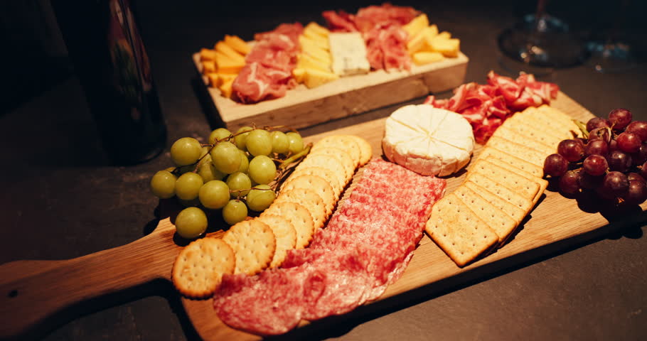 Cheese board, cold meat and fruit with crackers for snack, food or charcuterie for catering. Healthy, grapes and gourmet selection with fresh ingredients on wooden surface for nutrition or meal