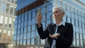 Senior woman smiling during video call in city - Powered by Shutterstock - Get 15% off with code: PIKWIZARD15
