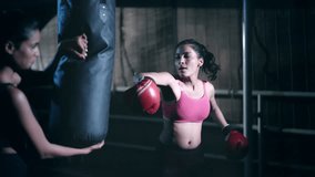 Indian young adult gen z woman in sportswear do sport training punching on bag at indoor place. Healthy athletic boxer female standing wear boxing gloves learn beating exercise workout at dark room - Powered by Shutterstock - Get 15% off with code: PIKWIZARD15