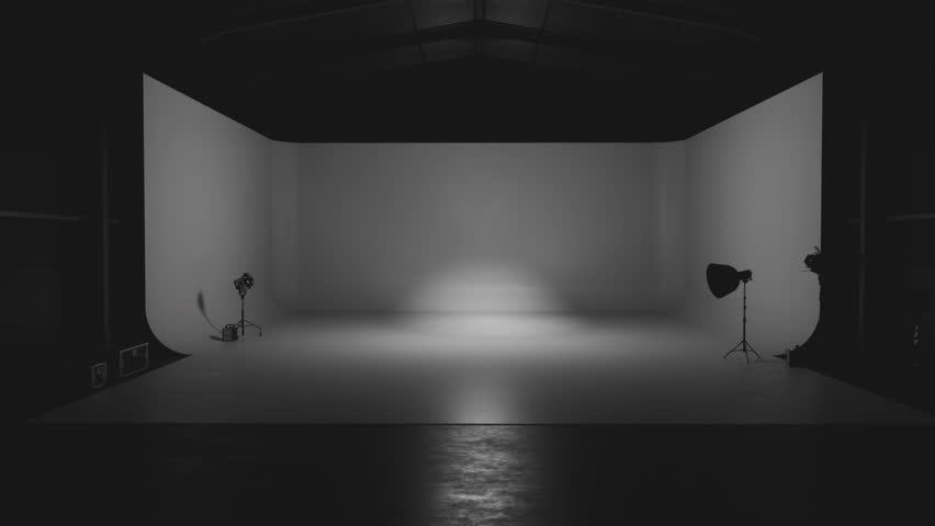 Professional lighting equipment illuminates a white cyclorama in an empty photo studio
