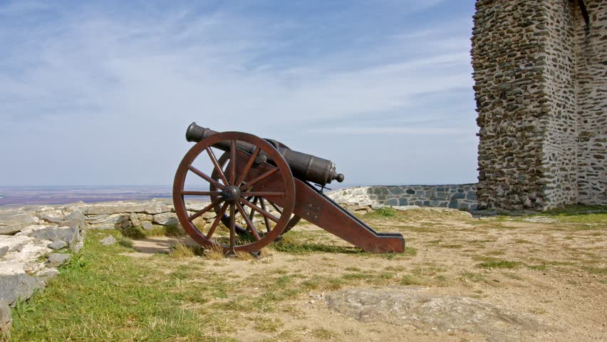 Historic cannon stands guard at ancient fortress under blue sky in peaceful landscape