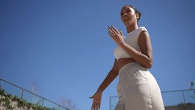 An empowered woman confidently walks outdoors under a clear blue sky, wearing a chic crop top and relaxed pants, blending fashion and fitness elegantly while enjoying the fresh air - Powered by Shutterstock - Get 15% off with code: PIKWIZARD15