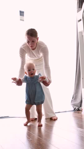 Mother and baby at home. Mom helping Child take first steps, emotional and heartwarming moment of early childhood development, parenting support, cozy indoor with natural light