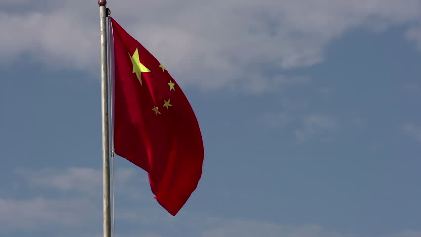 Flag of China. Flag of the People's Republic of China against the blue sky with white clouds. Slow Motion