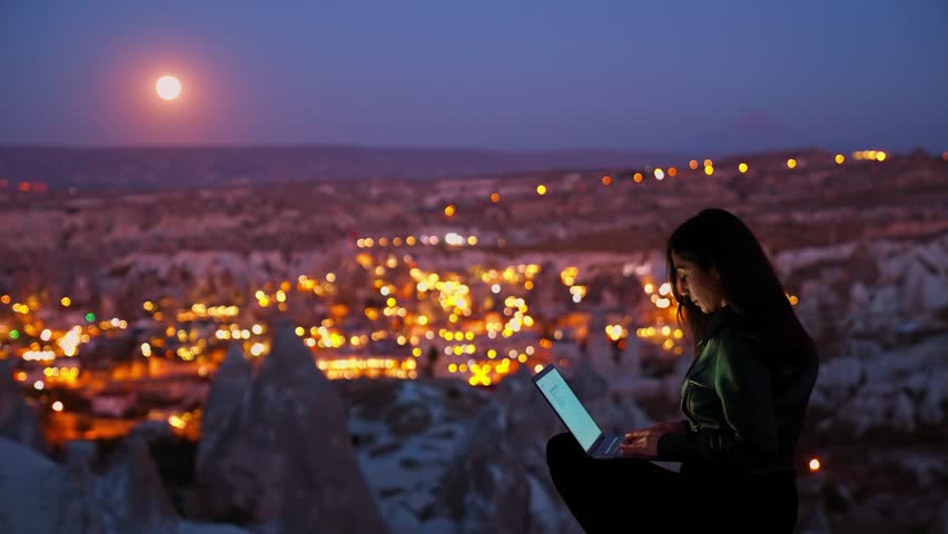 Woman Working on Laptop Under Full Moon with Cappadocia View