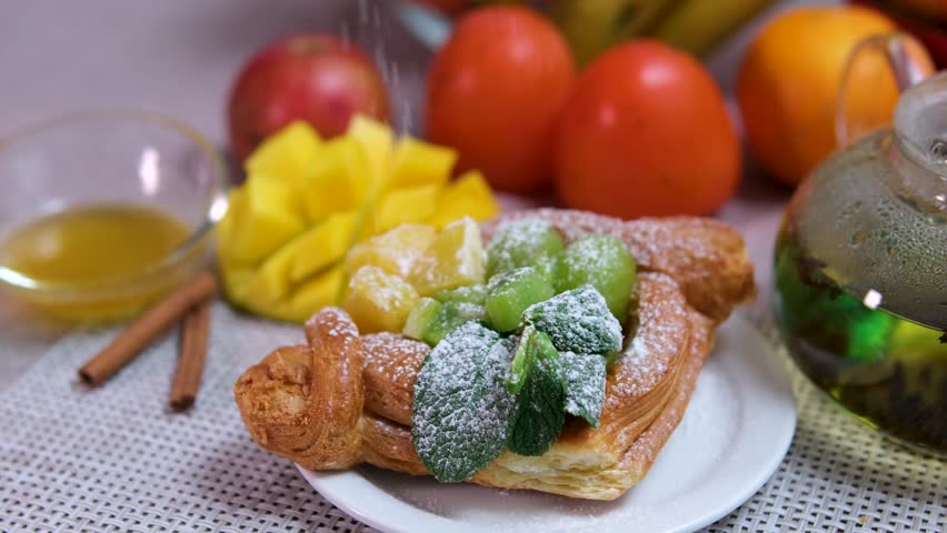 sprinkle with powdered sugar pastries with mint kiwi and other fruits Mango persimmon orange delicious tea with cinnamon