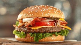 Delicious Hamburger with Cheese in Motion. Fresh Fast Food with Beautiful Bokeh Kitchen Background. Cheeseburger Ready to Eat. - Powered by Shutterstock - Get 15% off with code: PIKWIZARD15